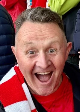 A man with a Forest scarf cheers at the camera