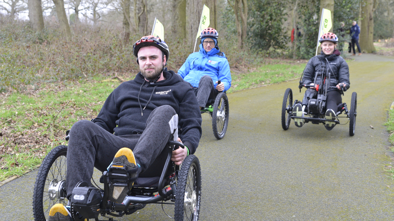 Three people riding adaptive trikes