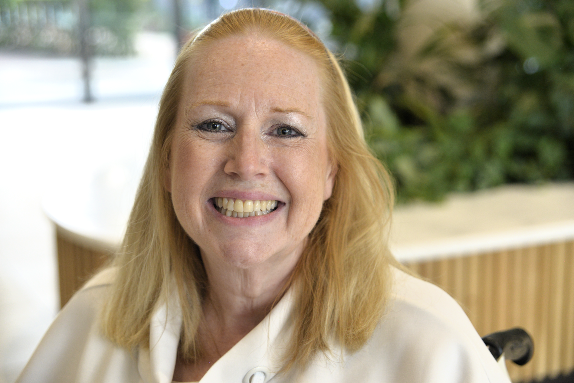A woman with shoulder-length blonde hair smiles at the camera